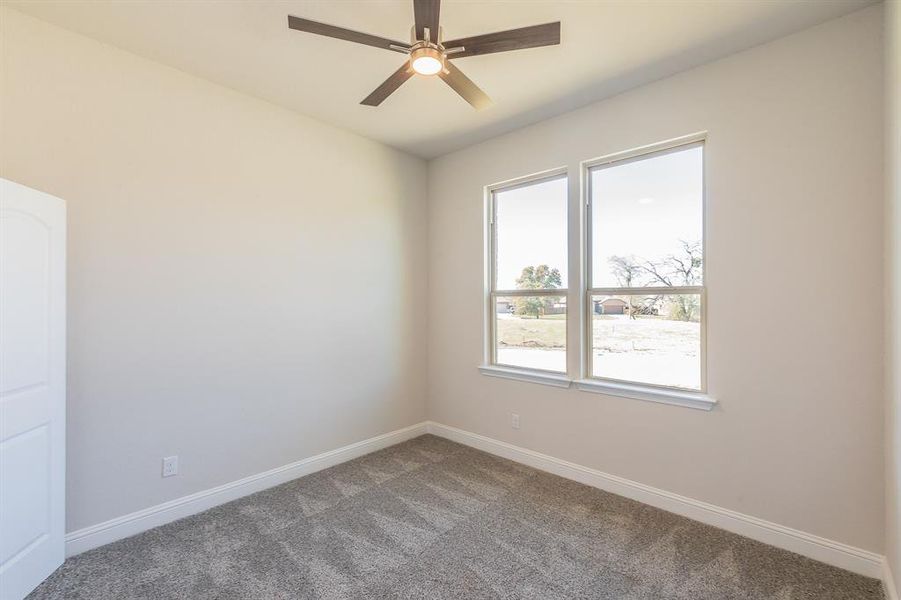 Carpeted spare room featuring ceiling fan