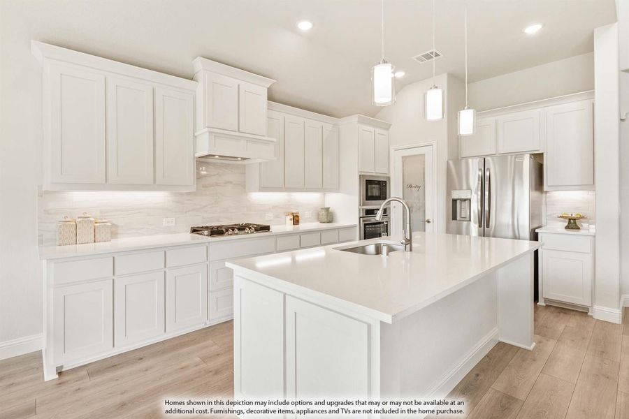White kitchen with large island, pendant lights, stainless steel appliances, and light wood floors