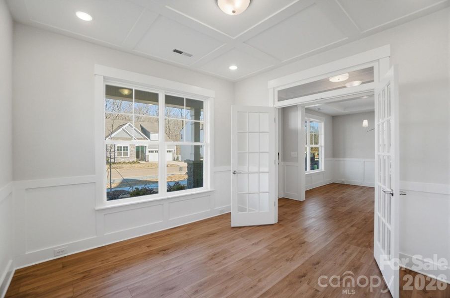 Office with faux coffered ceiling, French doors, and wainscoting
