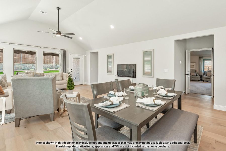 Open dining and living area with vaulted ceiling, ceiling fan, wood floors, and large dining table with bench seating Open dining and living area with vaulted ceiling, ceiling fan, wood floors, and large dining table with bench seating