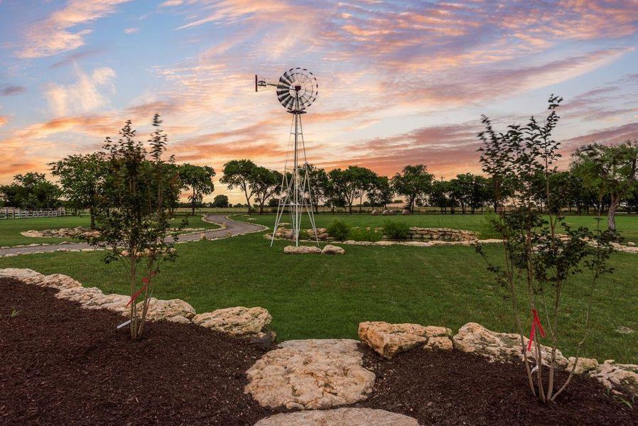 Expansive green space featuring a decorative windmill, meandering paved pathways, and mature trees lining the perimeter Expansive green space featuring a decorative windmill, meandering paved pathways, and mature trees lining the perimeter