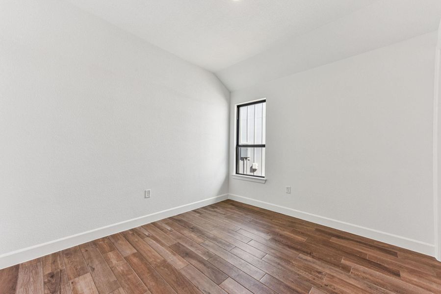 Spare room featuring lofted ceiling and wood finished floors