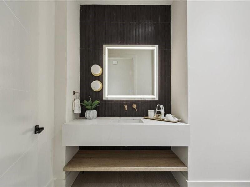 The main-floor powder bath features a sleek floating vanity and modern finishes for a contemporary look.