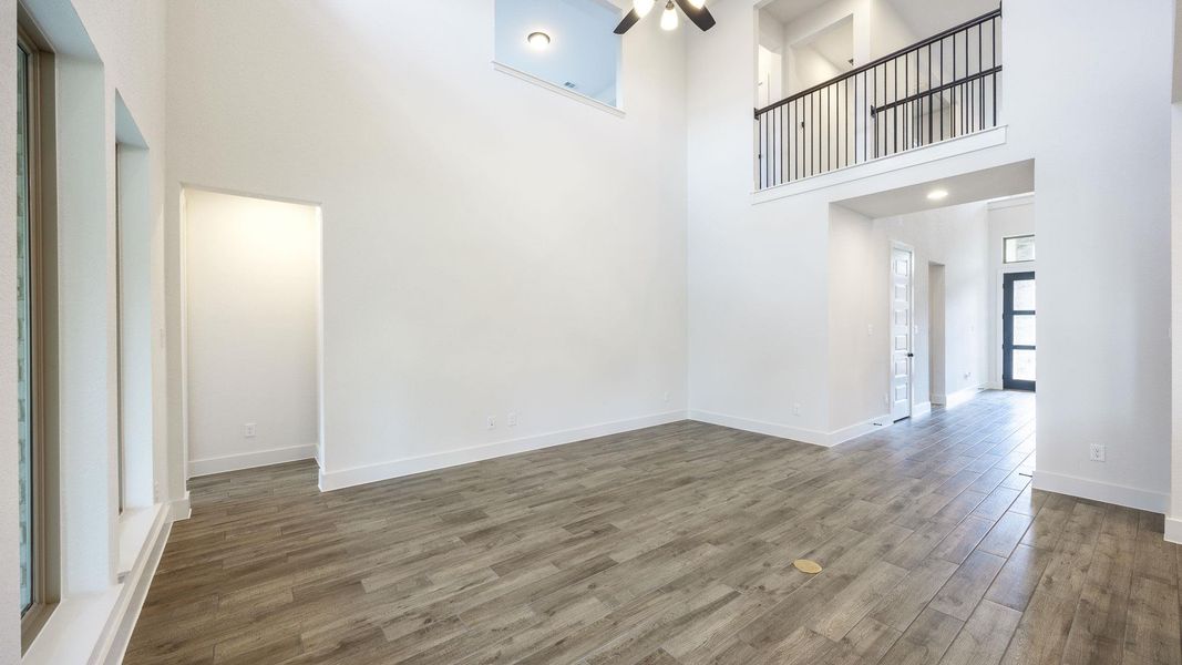 Unfurnished living room featuring a high ceiling and wood finished floors Unfurnished living room featuring a high ceiling and wood finished floors