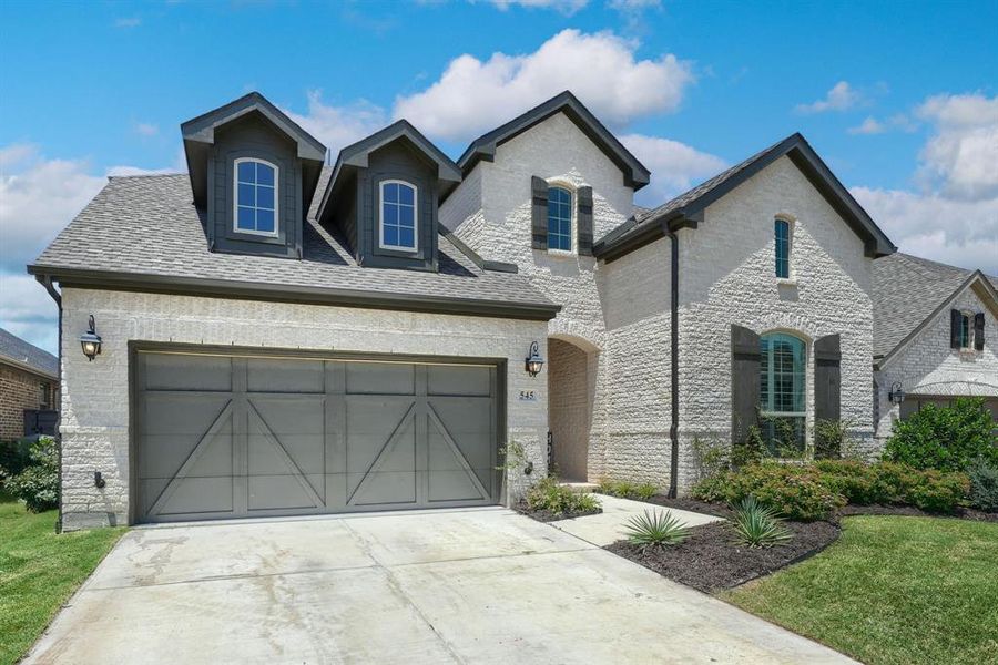 French country style house featuring a garage and a front yard