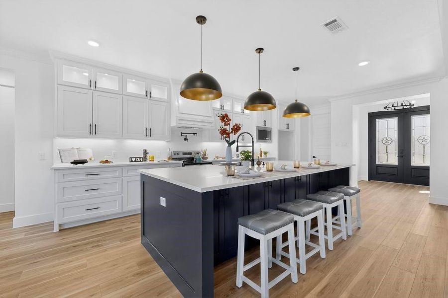 Kitchen with french doors, two tone cabinetry, a breakfast bar, decorative light fixtures, and light wood-style floors Kitchen with french doors, two tone cabinetry, a breakfast bar, decorative light fixtures, and light wood-style floors