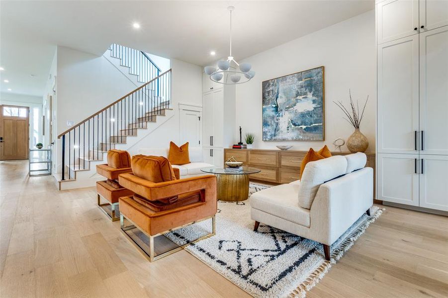 Living room featuring a high ceiling, a chandelier, and light hardwood / wood-style flooring