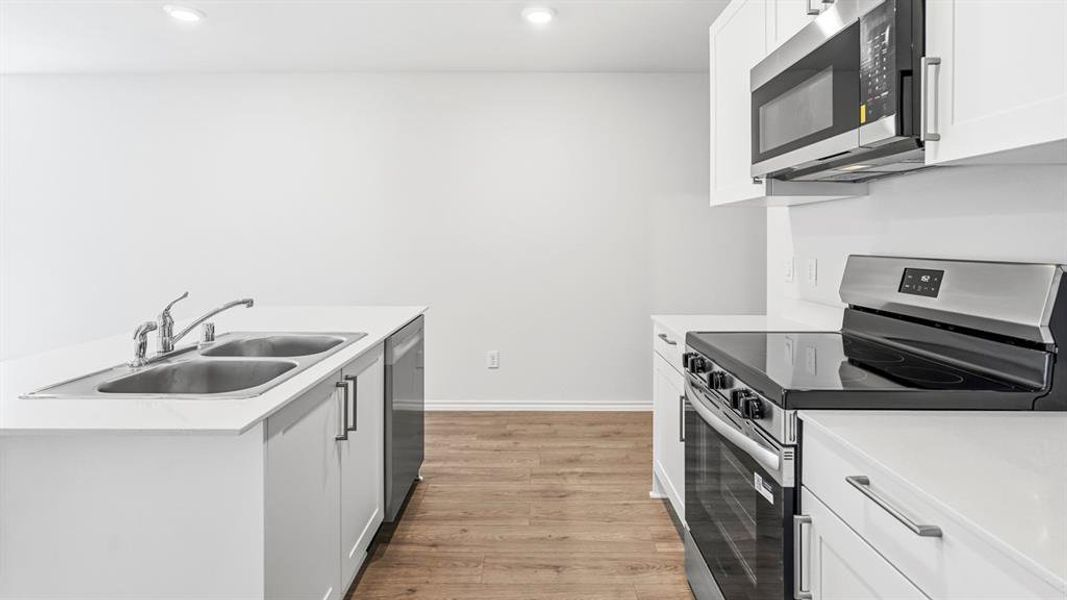 Kitchen with stainless steel appliances, white cabinetry, light wood-style flooring, recessed lighting, and an island with sink Kitchen with stainless steel appliances, white cabinetry, light wood-style flooring, recessed lighting, and an island with sink