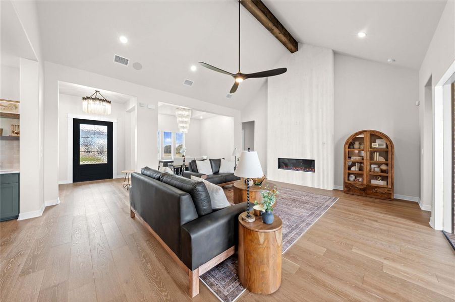 A well-lit interior showcases vaulted ceilings with exposed beams and recessed lighting, flowing into an inviting living area with a fireplace. A well-lit interior showcases vaulted ceilings with exposed beams and recessed lighting, flowing into an inviting living area with a fireplace.