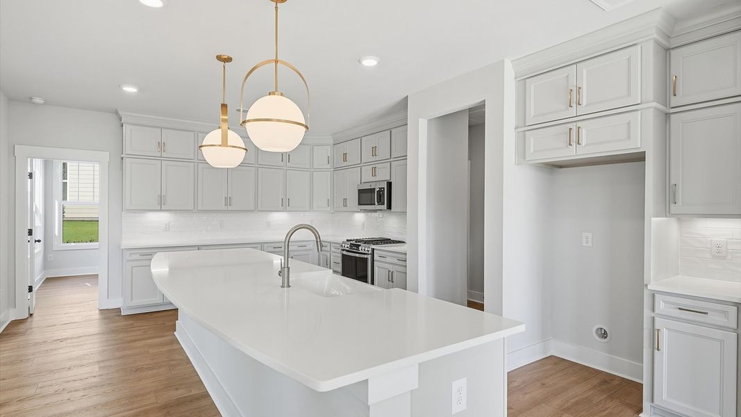 Spacious open-concept kitchen featuring stacked cabinetry and statement pendant lighting