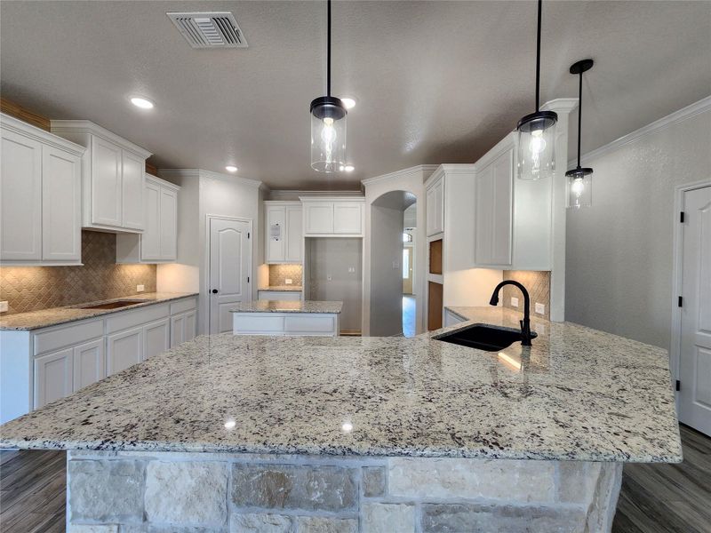 Kitchen with dark wood-style flooring, a peninsula, pendant lighting, and crown molding