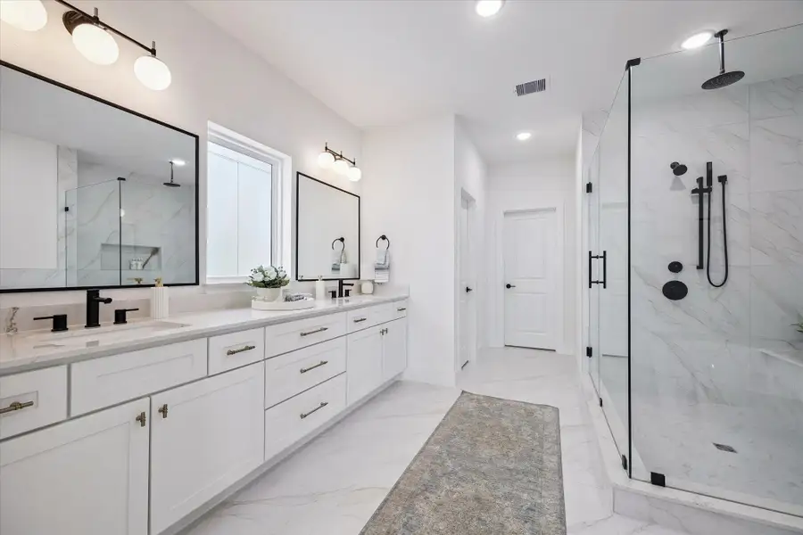 Riverway Homes are renowned for their luxurious bathrooms, featuring stunning designer tile and a freestanding tub within the spacious shower area, complete with both a rain shower and handheld shower head.