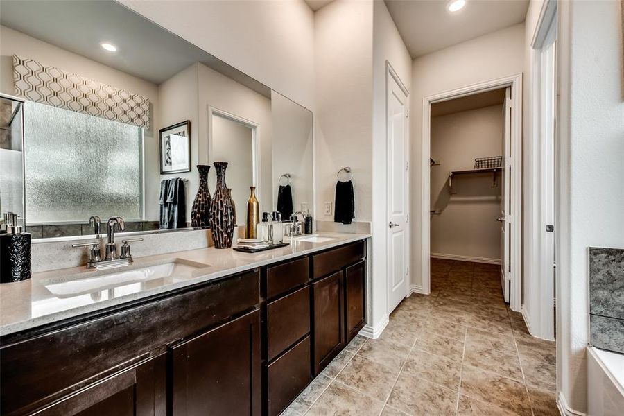 Bathroom with light tile patterned floors, double vanity, a bathtub, recessed lighting, and a walk in closet
