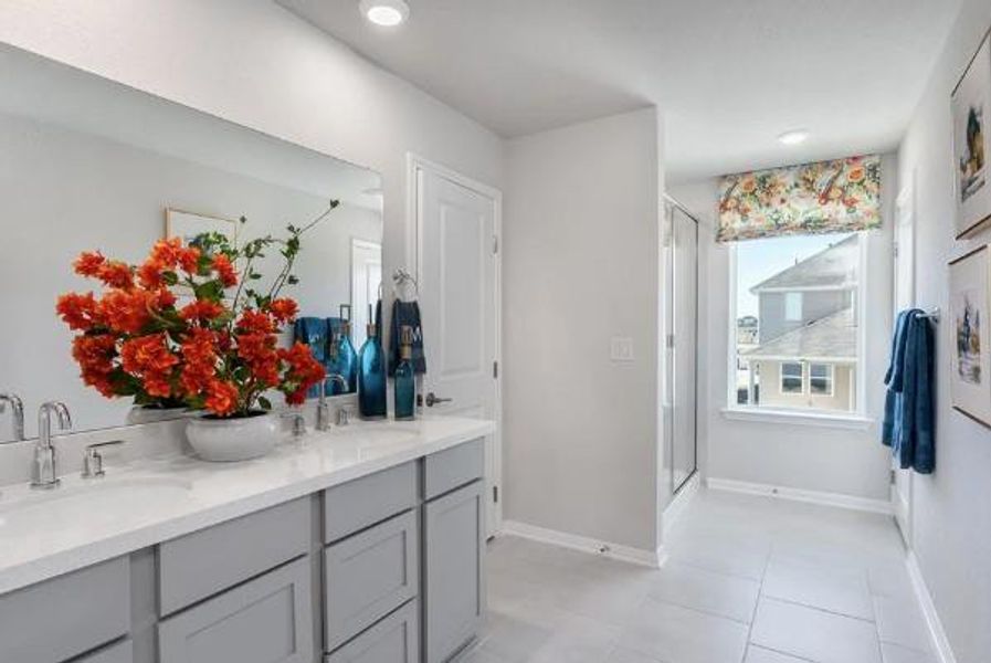 Bathroom featuring a stall shower, double vanity, a sink, and baseboards Bathroom featuring a stall shower, double vanity, a sink, and baseboards