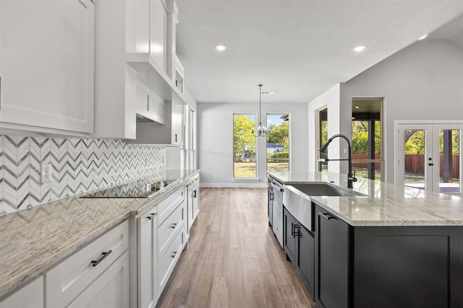 Kitchen featuring white cabinetry, light stone counters, recessed lighting, dark cabinetry, and pendant lighting