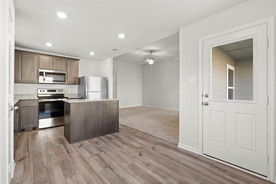 Kitchen featuring ceiling fan, a center island, light hardwood / wood-style floors, and stainless steel appliances
