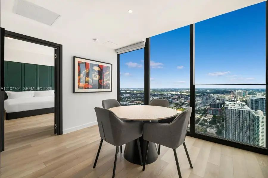 Floor-to-ceiling windows, wood-finish flooring, recessed lighting, and urban skyline backdrop