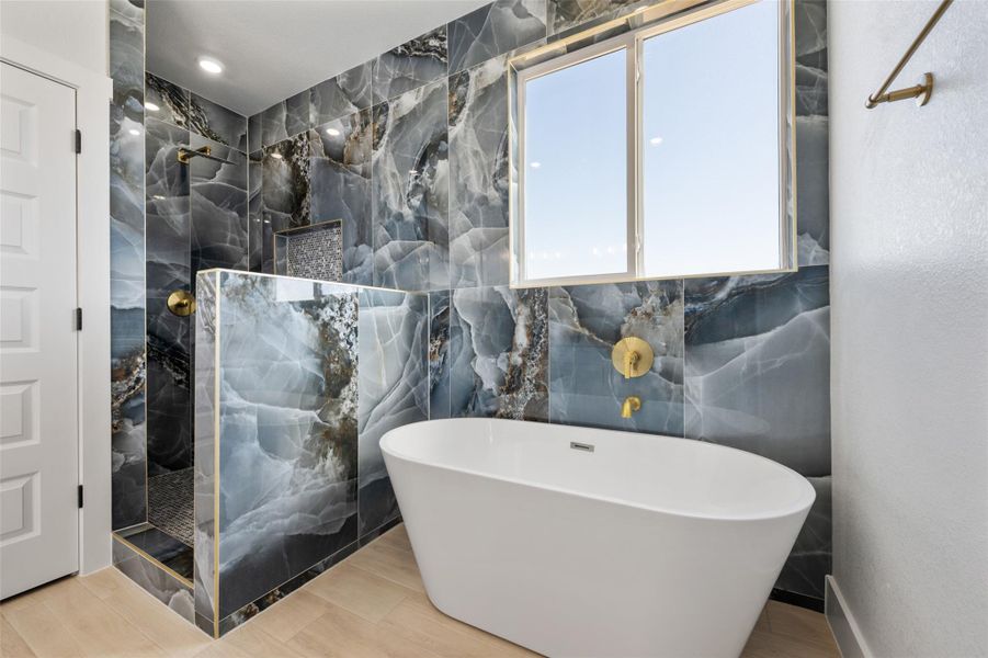Bathroom with a marble finish shower, a soaking tub, tile walls, and wood finished floors