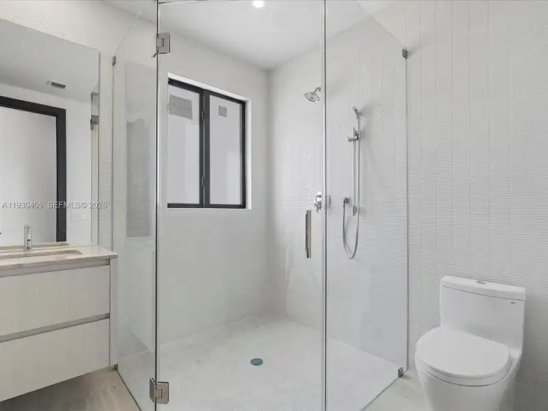 Walk-in shower with a glass enclosure, wall-mounted showerhead, hand-held sprayer, and stacked tile surround Walk-in shower with a glass enclosure, wall-mounted showerhead, hand-held sprayer, and stacked tile surround
