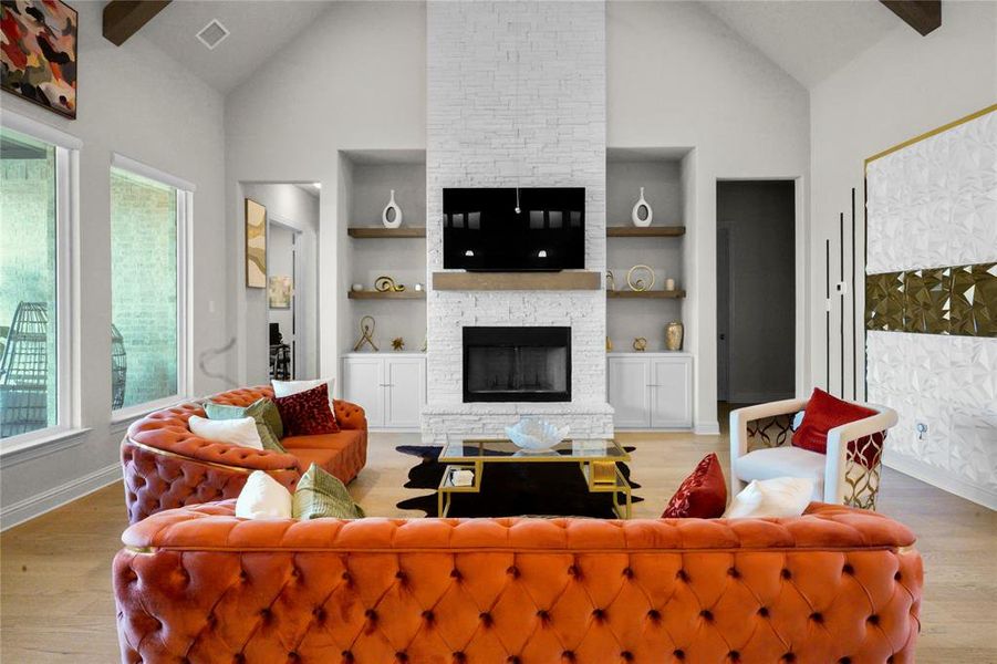 Living room featuring light wood-style flooring, high vaulted ceiling, a fireplace, and built in features Living room featuring light wood-style flooring, high vaulted ceiling, a fireplace, and built in features