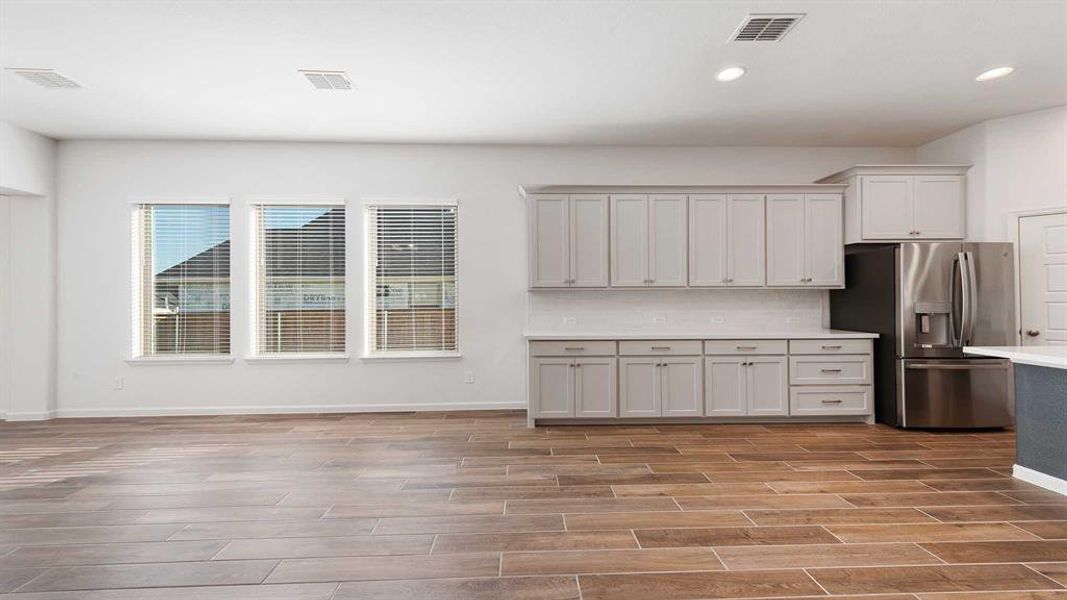 Kitchen with stainless steel refrigerator with ice dispenser, tasteful backsplash, light hardwood / wood-style flooring, and gray cabinetry