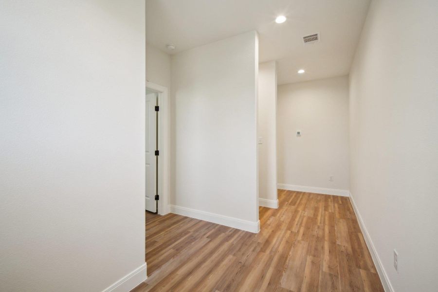Corridor with baseboards, visible vents, recessed lighting, and light wood-style floors Corridor with baseboards, visible vents, recessed lighting, and light wood-style floors