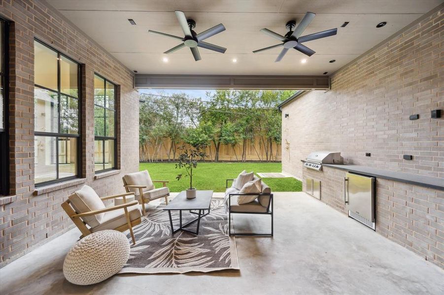 This spacious covered patio with a built-in outdoor kitchen, grill, and sink is perfect for entertaining. Overhead fans and recessed lighting provide comfort and style for gatherings in any season.