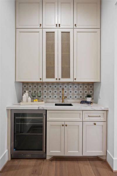 Showcasing a stylish wet bar with decorative tile backsplash, and a built-in wine cooler. Showcasing a stylish wet bar with decorative tile backsplash, and a built-in wine cooler.