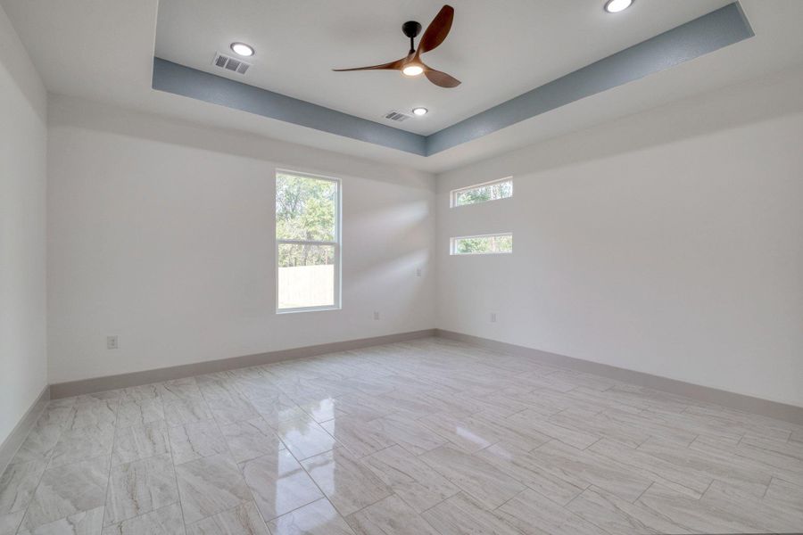 Empty room with a raised ceiling, ceiling fan, and recessed lighting Empty room with a raised ceiling, ceiling fan, and recessed lighting