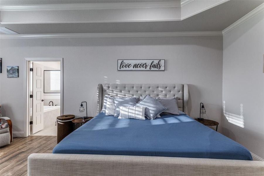 Bedroom featuring crown molding, wood finished floors, and ensuite bath