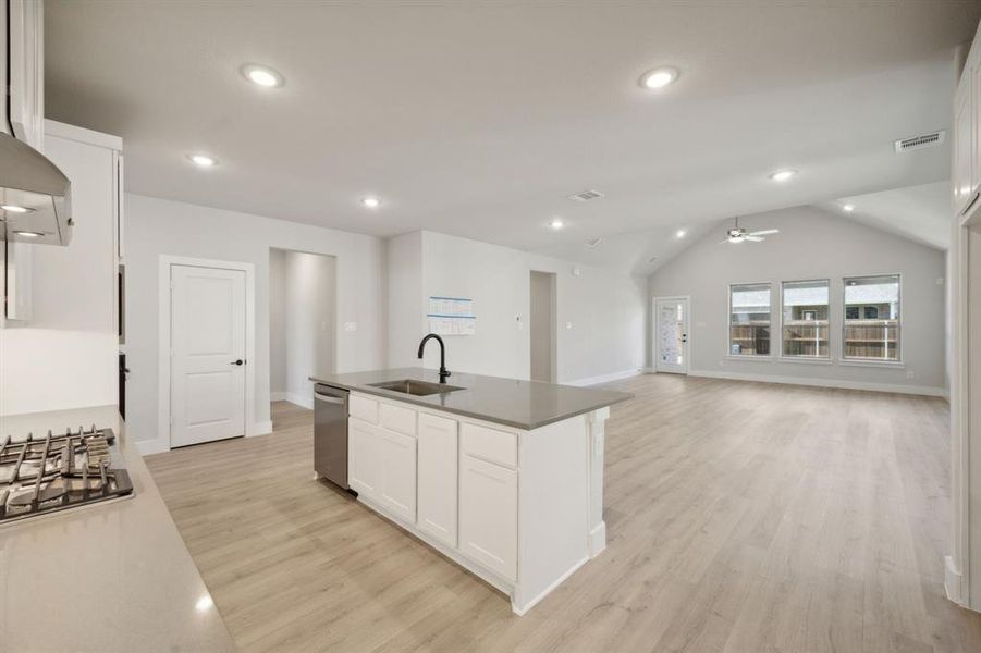 Kitchen with white cabinetry, sink, an island with sink, lofted ceiling, and appliances with stainless steel finishes