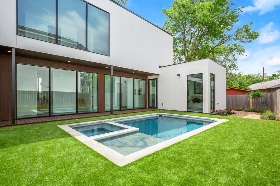 Back of property with a pool with connected hot tub, a patio area, and stucco siding