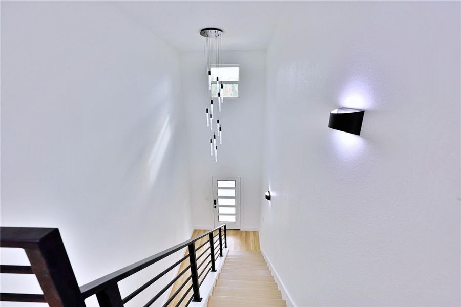 View from upstairs: high ceilings, chandelier, staircase, and modern lighting.