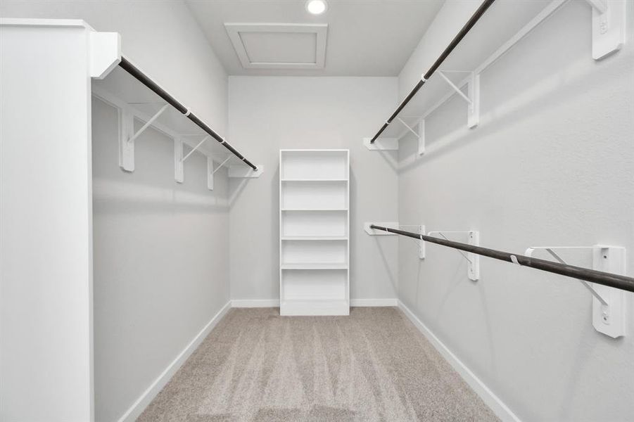 This generously sized closet boasts built-in shelving, providing ample room for organization. With high ceilings and recessed lighting, the ambiance is both bright and welcoming. Plush carpeting underfoot enhances the comfort, while warm paint tones add a touch of coziness. Sample photo of completed home with similar floor plan. As-built interior colors and selections may vary.