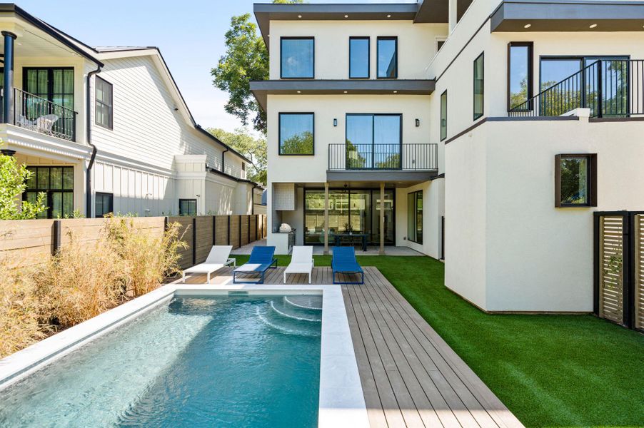 An inviting backyard oasis showcases a pristine swimming pool, manicured lawn, and modern multi-level architecture. An inviting backyard oasis showcases a pristine swimming pool, manicured lawn, and modern multi-level architecture.