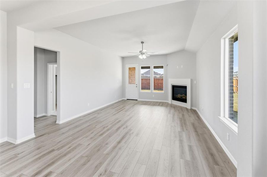 Unfurnished living room with a fireplace, light wood-type flooring, a ceiling fan, and vaulted ceiling