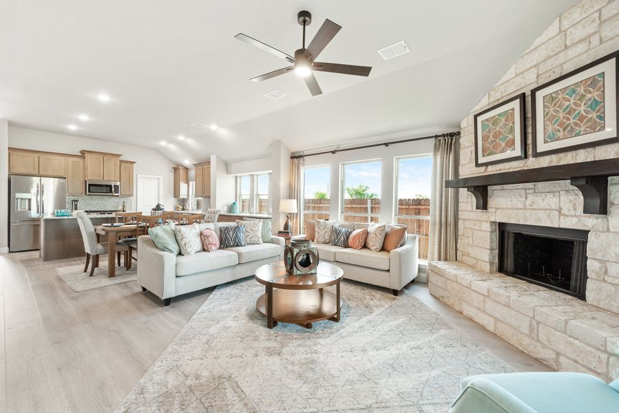 Open-concept living room with stone fireplace, ceiling fan, and hardwood floors, open to kitchen and dining area. Open-concept living room with stone fireplace, ceiling fan, and hardwood floors, open to kitchen and dining area.