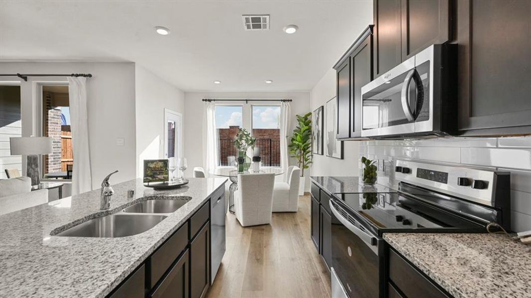 Kitchen featuring appliances with stainless steel finishes, light stone counters, light wood finished floors, recessed lighting, and decorative backsplash