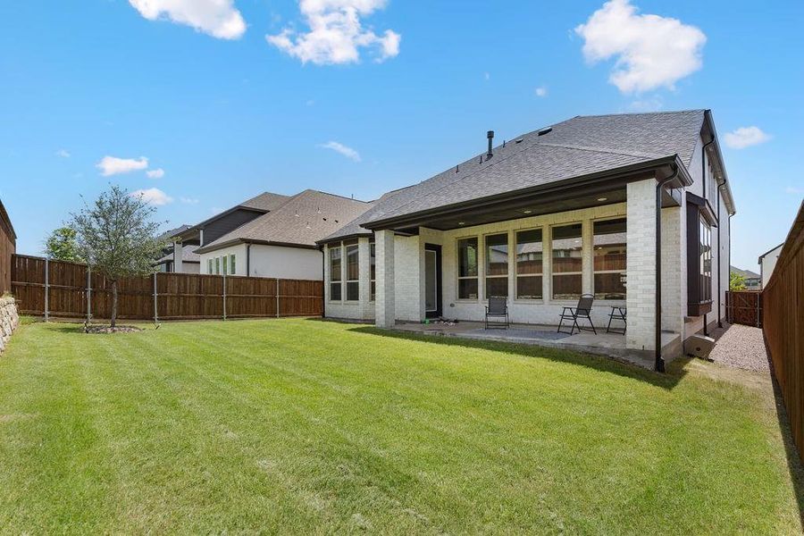 Spacious backyard featuring a manicured lawn, full privacy fencing, and a covered patio Spacious backyard featuring a manicured lawn, full privacy fencing, and a covered patio