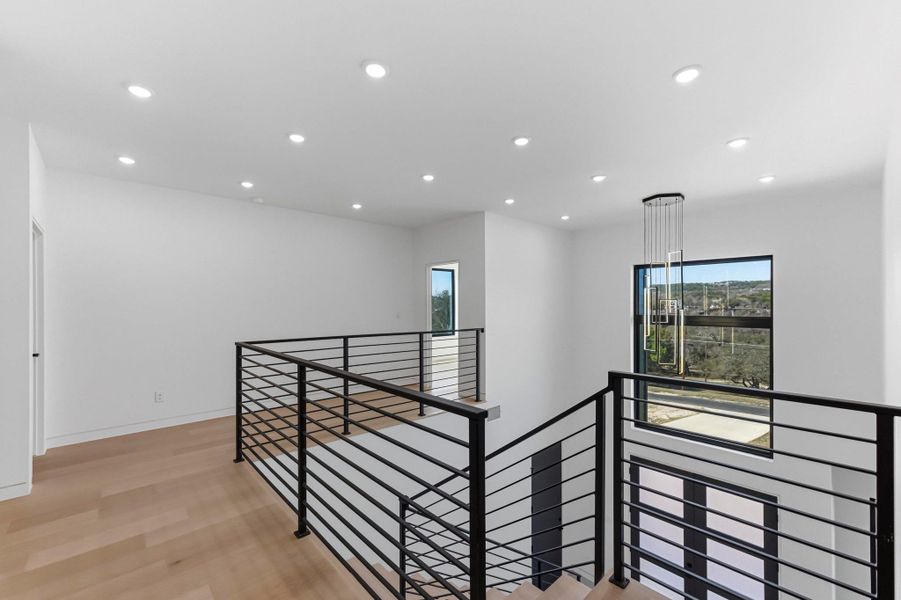 Corridor with an upstairs landing, recessed lighting, plenty of natural light, and light wood-type flooring