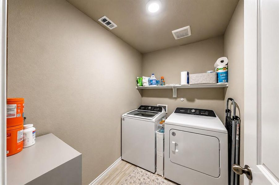 Dedicated laundry space with light neutral wall tones, recessed lighting, and a built-in shelving unit