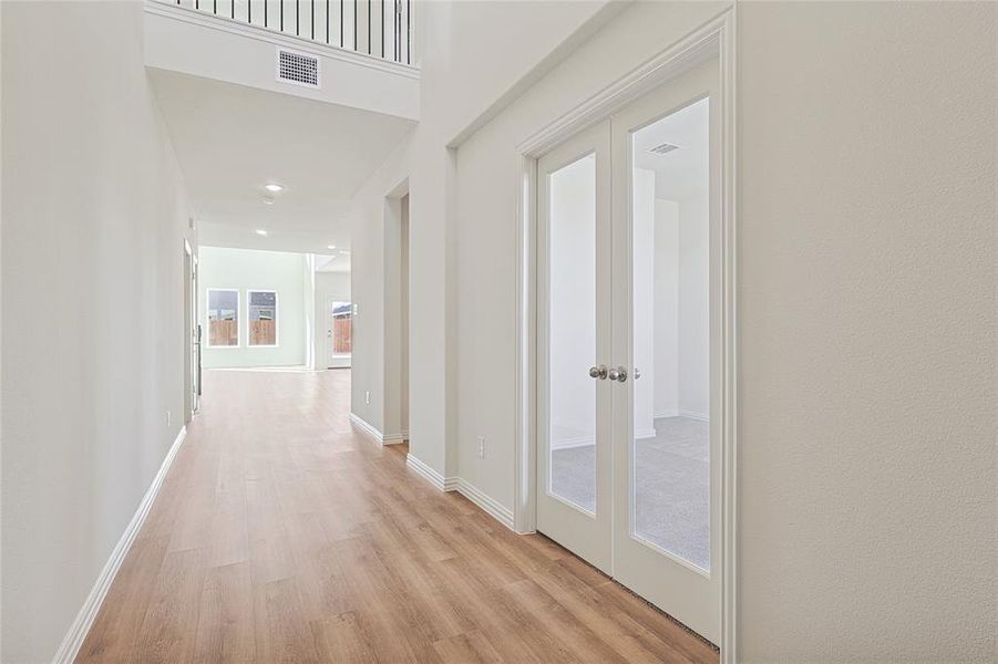 Corridor with light wood finished floors, recessed lighting, and french doors