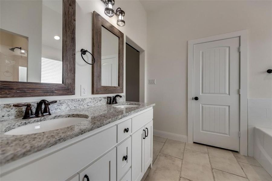 Bathroom with double vanity, a tub to relax in, and light tile patterned floors