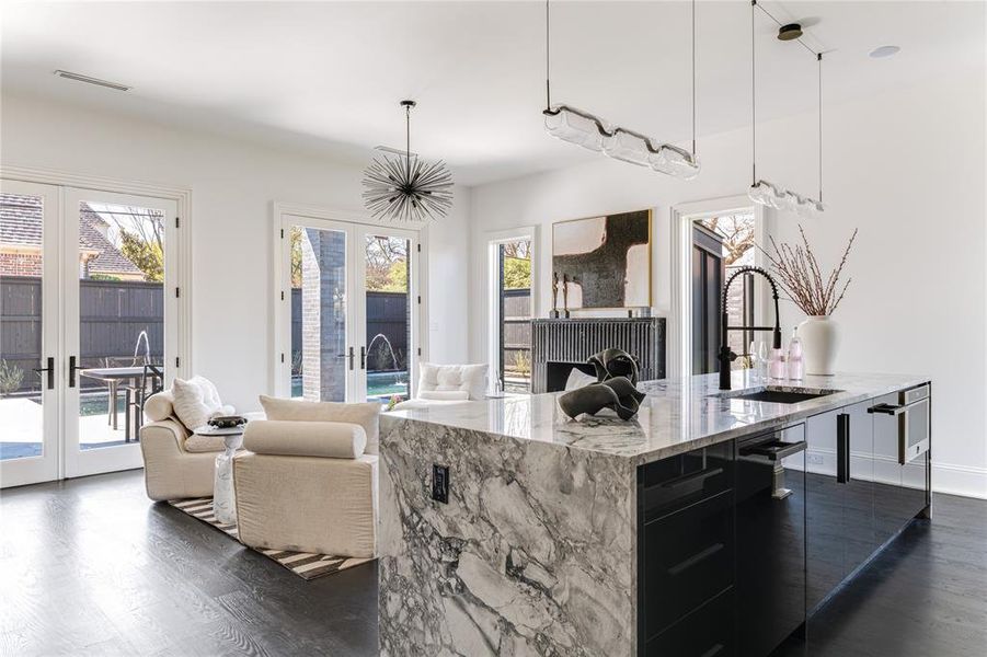 Kitchen featuring a sink, dark cabinets, and light stone counters