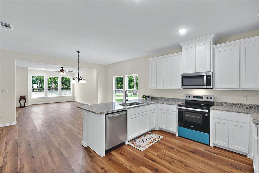 Kitchen with white cabinets, appliances with stainless steel finishes, a sink, a peninsula, and visible vents Kitchen with white cabinets, appliances with stainless steel finishes, a sink, a peninsula, and visible vents