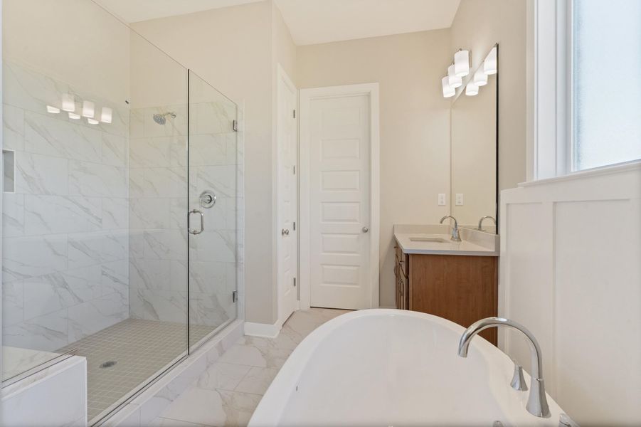 Bathroom with vanity, a soaking tub, a shower stall, and light marble finish flooring