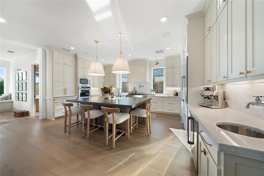 Kitchen featuring a center island, backsplash, sink, appliances with stainless steel finishes, and decorative light fixtures