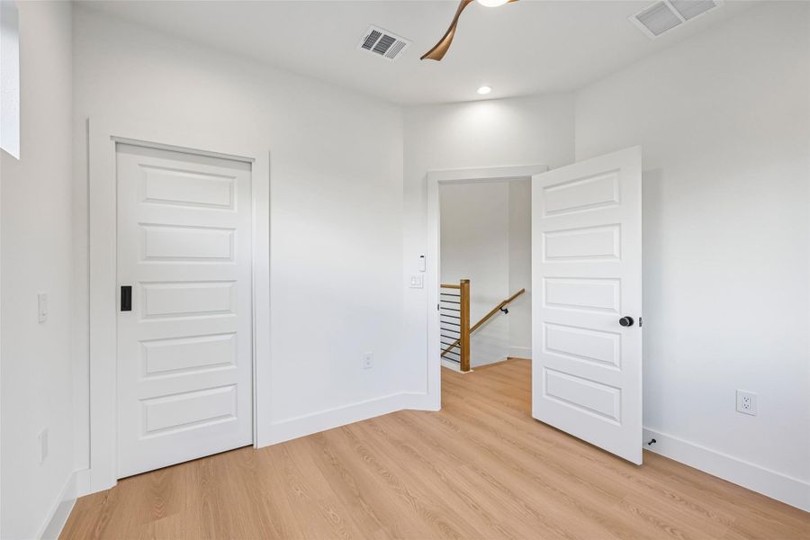 Natural light illuminates this secondary bedroom with durable, easy-to-maintain flooring and crisp, modern doors.
