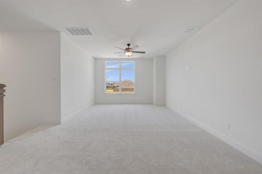 Spacious room featuring light gray carpeting, crisp white walls, and a large multi-pane window