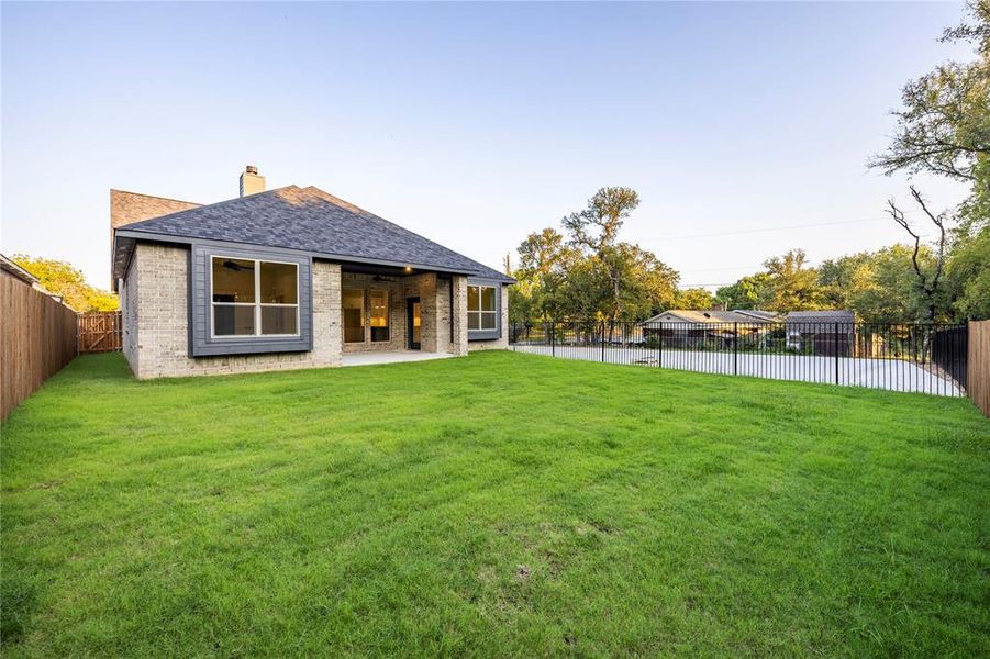 Back of house featuring a patio area, roof with shingles, a chimney, brick siding, and a fenced backyard